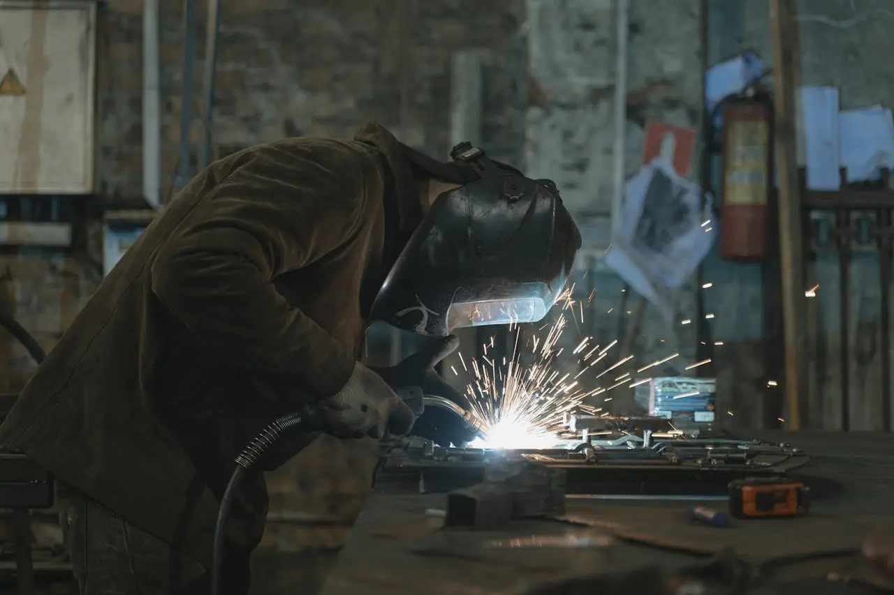 Arbeiter schweisst an Metall her um. Funken sprühen.